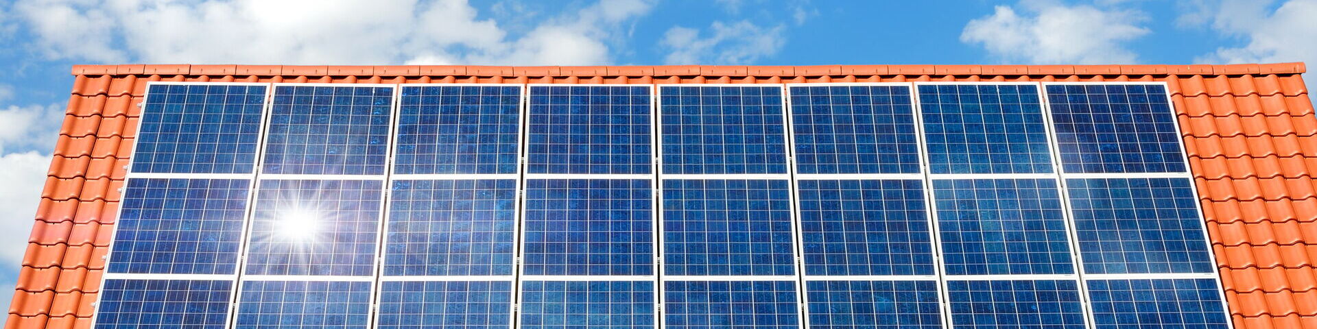 Das Bild zeigt ein Hausdach mit roten Dachziegeln, welches vollständig mit Solarmodulen bestückt ist.