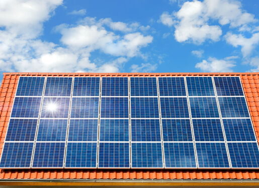 Das Bild zeigt ein Hausdach mit roten Dachziegeln, welches vollständig mit Solarmodulen bestückt ist.