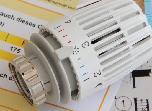 Ein Thermostat, das auf verschiedenen Dokumenten und Euro-Banknoten liegt.