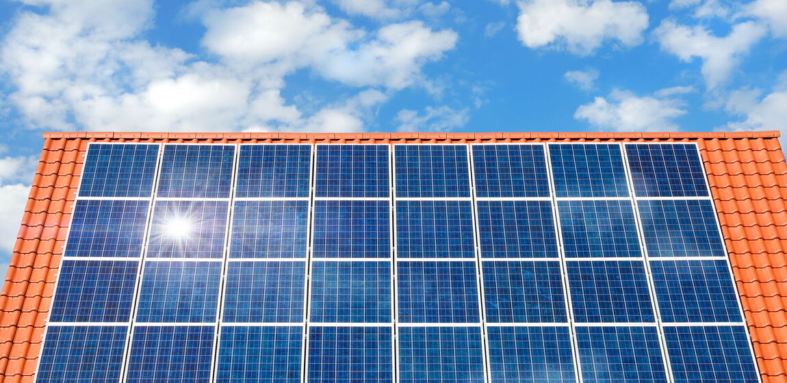 Das Bild zeigt ein Hausdach mit roten Dachziegeln, welches vollständig mit Solarmodulen bestückt ist.
