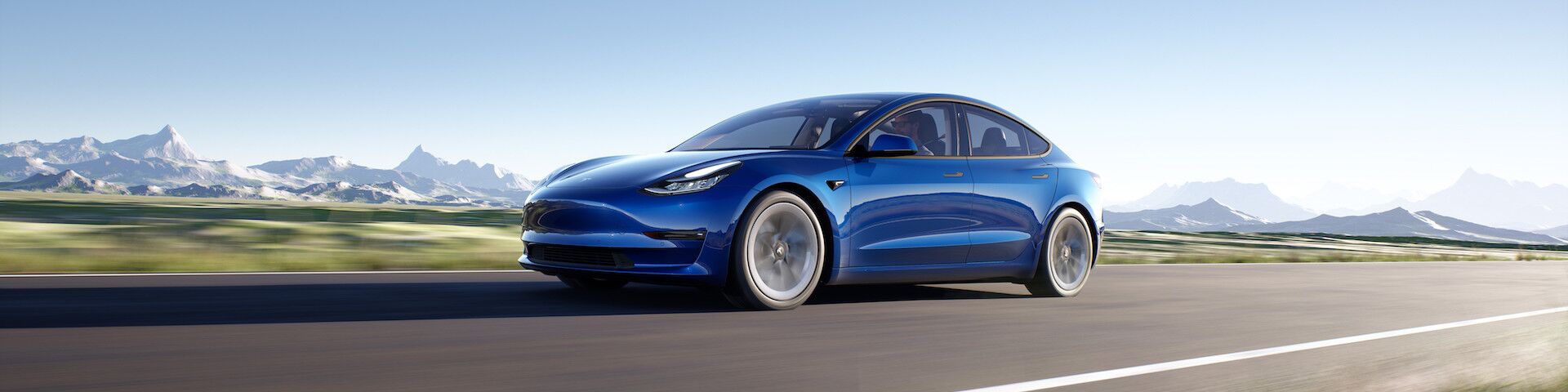 Das Bild zeigt ein blaues Elektroauto, den Tesla Model 3, das auf einer Straße fährt, mit Bergen im Hintergrund. Das Auto hat ein schlankes und modernes Design, mit einer glatten Karosserie und aerodynamischen Merkmalen.