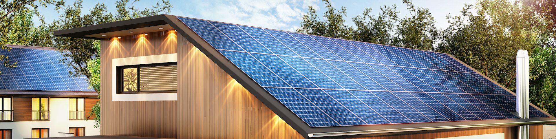 Das Bild zeigt ein modernes Haus mit einem schrägen Dach, das mit Solarpaneelen bedeckt ist. Das Haus hat eine Holzfassade und große Fenster.