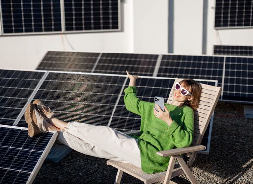Das Bild zeigt eine Dame. Sie liegt in Ihrem Liegestuhl, trägt einen grünen Pullover und eine weiße Sonnenbrille. Neben ihr befindet sich ein Solarpark.