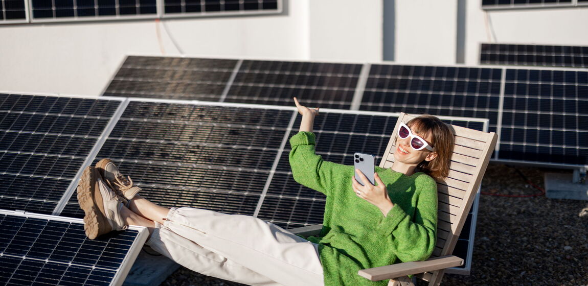 Das Bild zeigt eine Dame. Sie liegt in Ihrem Liegestuhl, trägt einen grünen Pullover und eine weiße Sonnenbrille. Neben ihr befindet sich ein Solarpark.