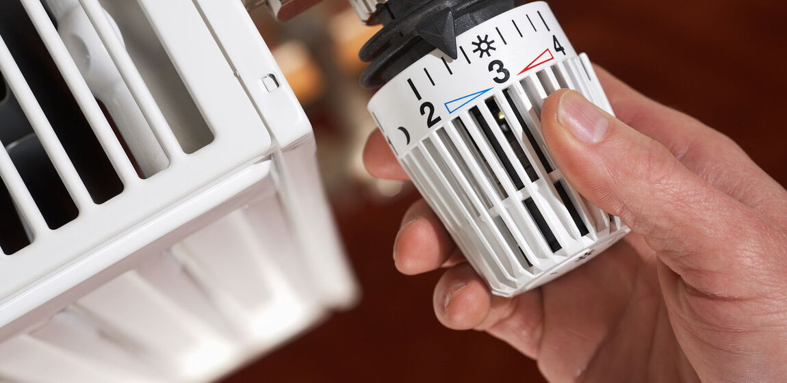 Auf dem Motiv ist eine Hand an einem Heizungsthermostat zu sehen.