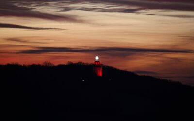 Ingelummer Kerz in Ingelheim bei Sonnenuntergang. Der Turm hat ein helles weißes Licht an der Spitze und ist mit roten Lichtern um seine Struktur herum beleuchtet.