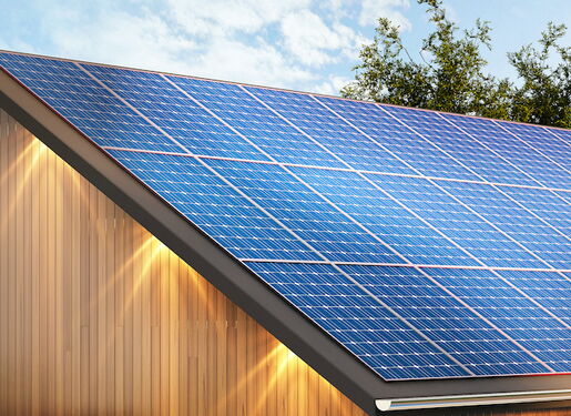 Das Bild zeigt ein modernes Haus mit einem schrägen Dach, das mit Solarpaneelen bedeckt ist. Das Haus hat eine Holzfassade und große Fenster.