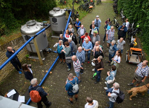 Das Bild zeigt zwei PFAS-Aktivkohlefilter in Heidesheim. Das Bild wurde beim Wasserradeln-Tag aufgenommen. Zu sehen sind außerdem etliche Zuhörer beim Vortrag von Lisa Gehrig zu den Filtern.