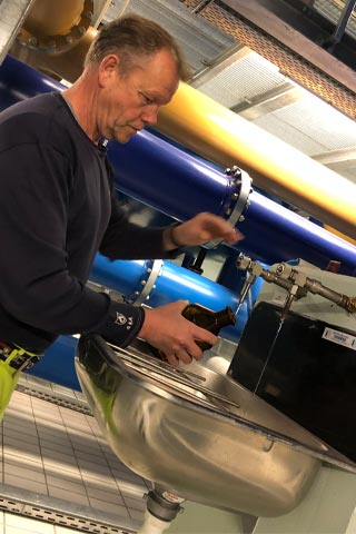Walter Berg füllt eine Flasche am Wasserhahn