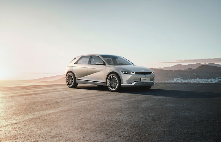 stehender Hyundai Ioniq 5 im Vordergrund und im Hintergrund die Berge