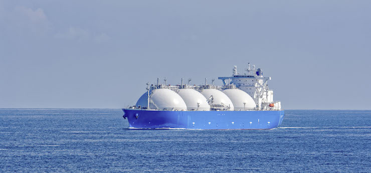 Ein Gasschiff mit 4 großen, weißen kugelförmigen Tanks auf dem Ozean. Der Himmel ist klar und blau, und das Wasser ist ruhig.