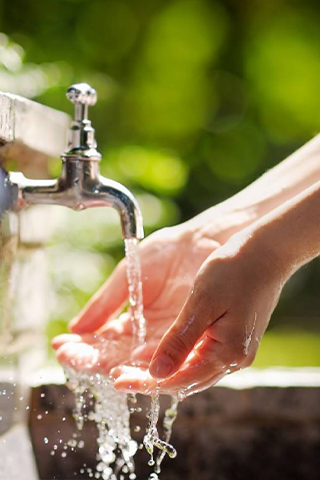 Ein Paar Hände, die unter einem laufenden Wasserhahn gewaschen werden.