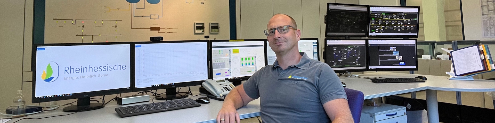 Alexander Reitz an seinem Arbeitsplatz, der Leitstelle mit vielen Monitoren im Hintergrund.