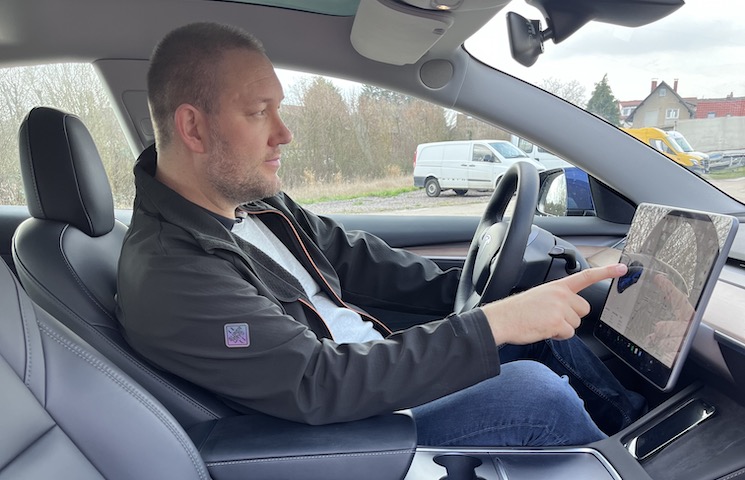 Frank Hilbrath auf dem Fahrersitz seines Autos und mit dem Touchscreen-Display auf dem Armaturenbrett interagiert.