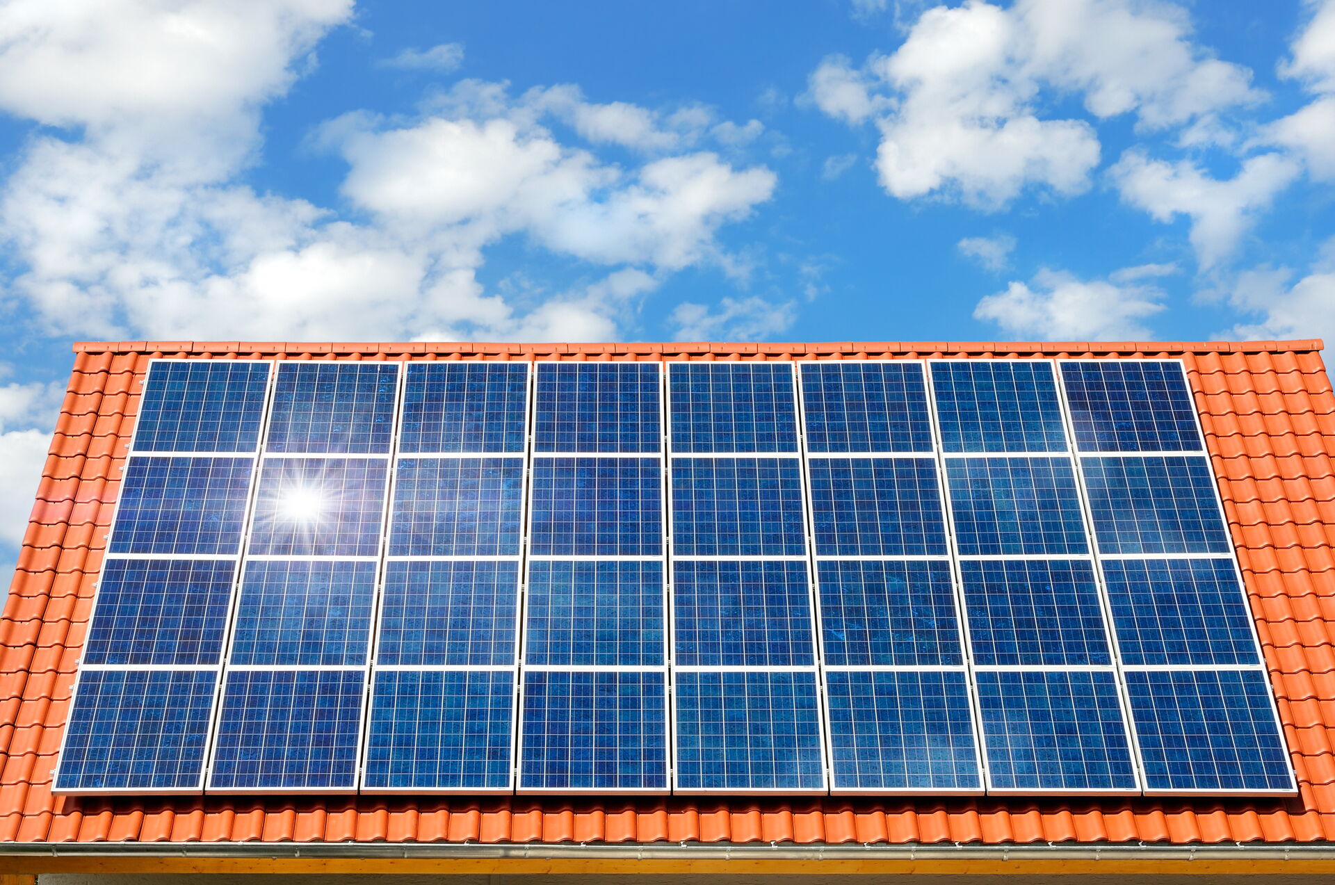 Das Bild zeigt ein Hausdach mit roten Dachziegeln, welches vollständig mit Solarmodulen bestückt ist.