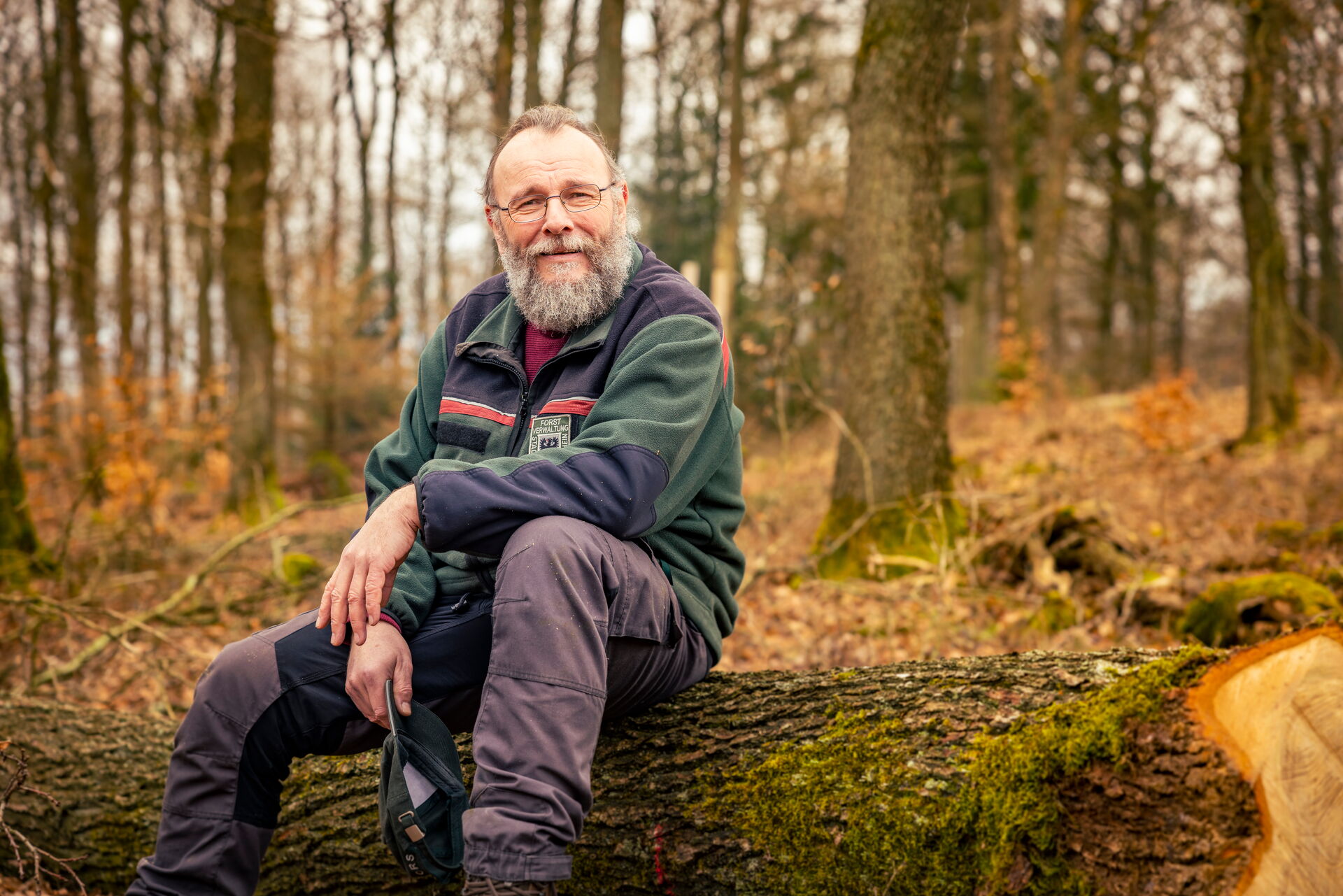 Das Bild zeigt den Ingelheimer Stadtwald-Förster Florian Diehl. Er sitzt im Ingelheimer Stadtwald auf einem Baumstamm und trägt seine Mütze in der Hand.