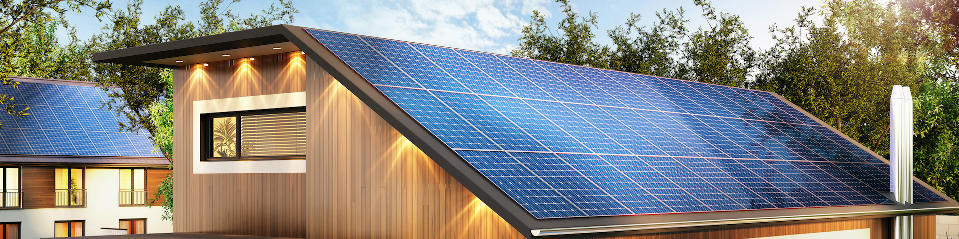 Das Bild zeigt ein modernes Haus mit einem schrägen Dach, das mit Solarpaneelen bedeckt ist. Das Haus hat eine Holzfassade und große Fenster.
